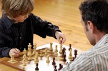 Boy playing chess with his father